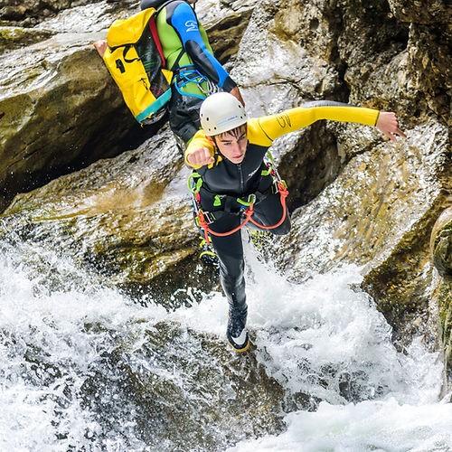 Eine Person springt beim Canyoning in der Starzlachklamm von einem Felsen